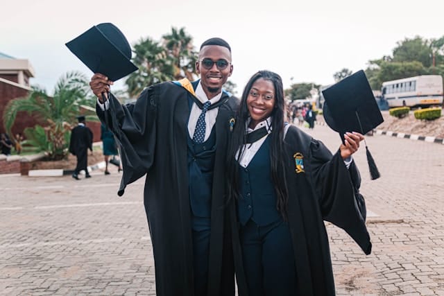 man and lady in academic dress standing on concrete