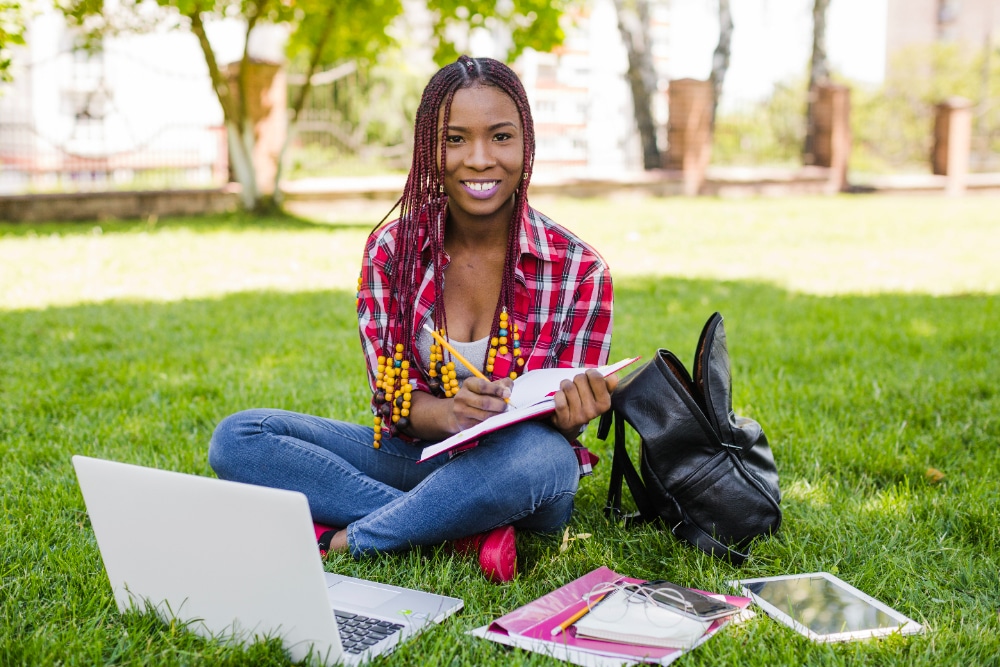 student with laptop sitting on grass